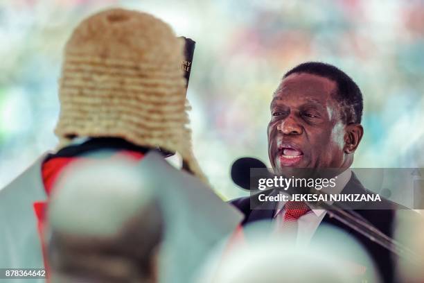 New interim Zimbabwean President Emmerson Mnangagwa holds the Holy Bible as he is officially sworn-in by Chief judge of the Supreme Court, Chief...