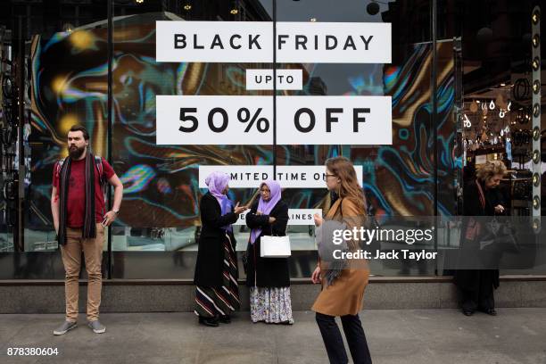 People stand in front of a shop with a Black Friday sale display on Oxford Street on November 24, 2017 in London, England. British retailers offer...