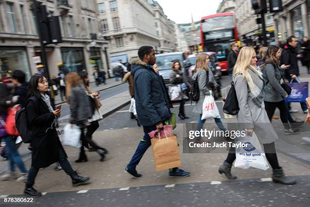 Shoppers carry bags as they cross the road along Oxford Street on November 24, 2017 in London, England. British retailers offer deals on their...