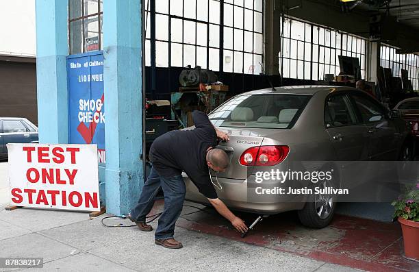 Thomas Zielin inserts a probe into the tailpipe of a car while performing an emissions test at Smog Queen May 18, 2009 in San Francisco, California....