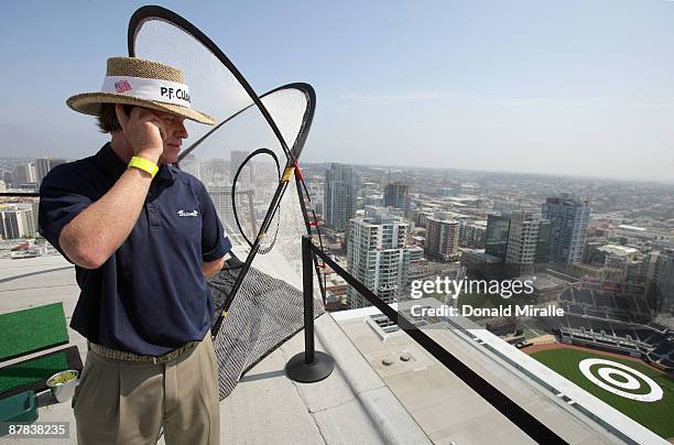 Player Briny Baird talks to his caddie as he prepares to hit off the roof of the Omni Hotel attempting to land a golf ball on a bulls-eye planted in...