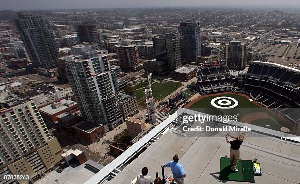 Player Briny Baird hits off the roof of the Omni Hotel attempting to land a golf ball on a bulls-eye planted in right-center field at PETCO Park as...