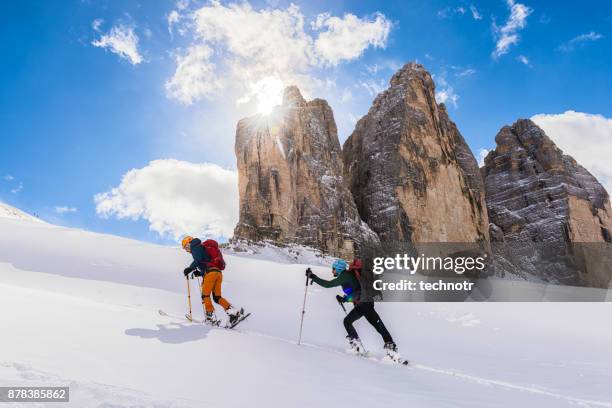 vista laterale di due giovani sciatori maschi allo sci alpinismo nelle dolomiti - sci alpinismo foto e immagini stock