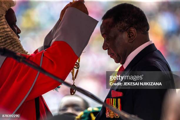 New interim Zimbabwean President Emmerson Mnangagwa receives the chain and sash of office from the Chief judge of the Supreme Court, Chief Justice...