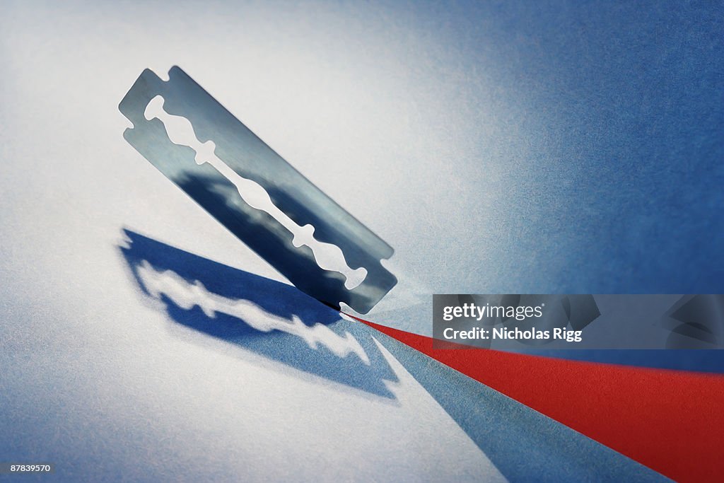 Razor blade cutting blue paper