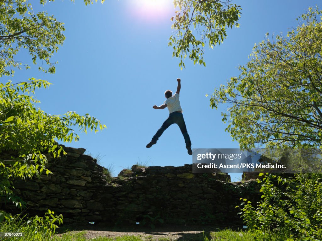 Man jumping for joy from top of rock wall