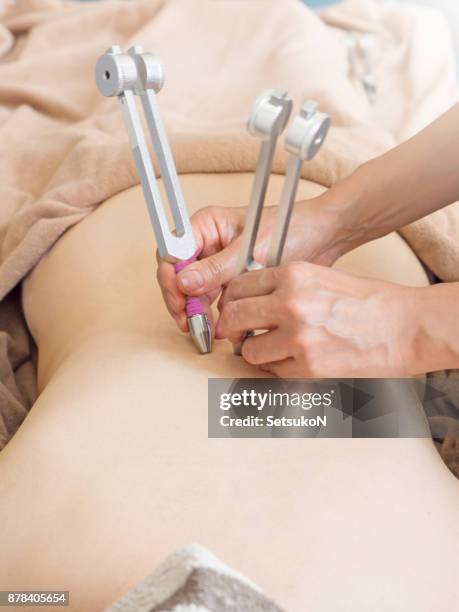 woman recieving tuning fork therapy - tuning stock pictures, royalty-free photos & images