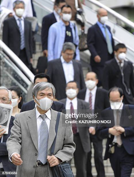 People wearing facemasks walk on their way to their offices in Kobe, Hyogo prefecture, in western Japan on May 19, 2009. Japan closed more than 4,000...