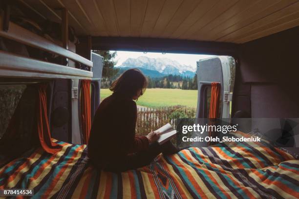 Woman reading book  in camper van with view on Alps