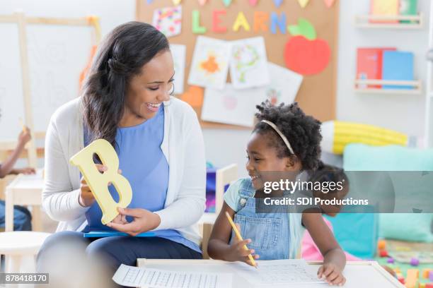 preschool teacher helps student with alphabet - back to school party stock pictures, royalty-free photos & images