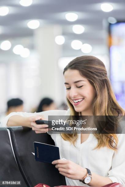 young woman checks in on smart phone at airport terminal - transcontinental railroad stock pictures, royalty-free photos & images