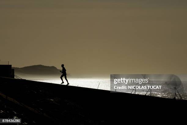 Man runs on a pier on November 23, 2017 at La Teste-de-Buch in the Arcachon bassin, southwestern France. / AFP PHOTO / NICOLAS TUCAT