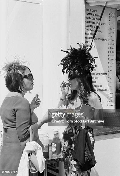 Couple of fashionable ladies tuck into fish and chips before a race at Epsom, June 2007. Epson Downs Racecourse is where the iconic Derby Festival...