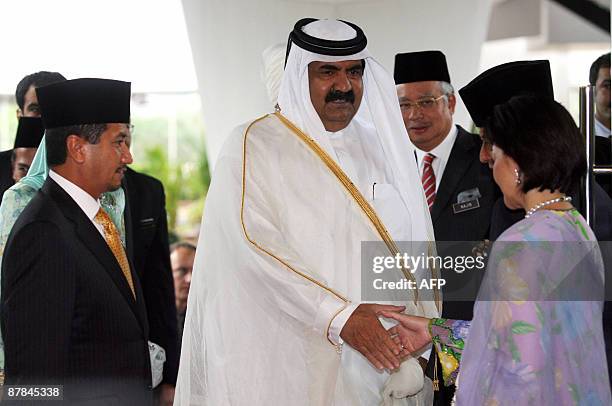 The Emir of Qatar, Sheikh Hamad Khalifa Al-Thani shakes hands with an unidentified woman, flanked by Malaysia's King Tuanku Mizan Zainal Abidin...
