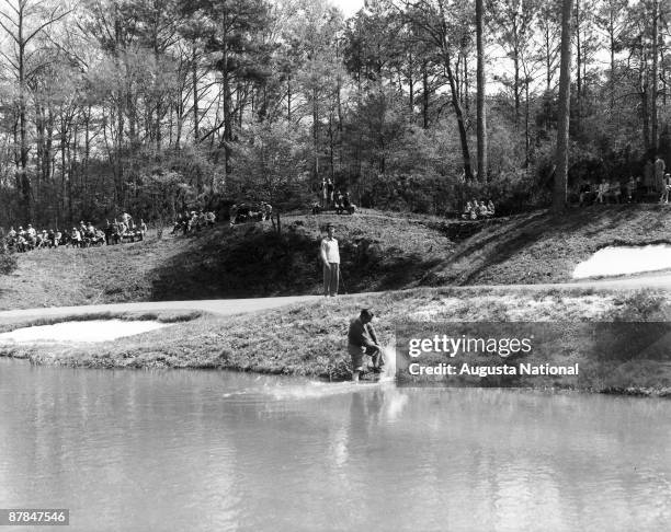 1930s: Ky Lafoon attempts to blast from the edge of Rae's Creek onto the 12th green during a 1930s Masters Tournament at Augusta National Golf Club...