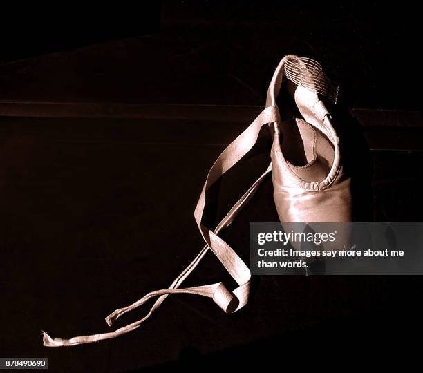 a single ballet shoe forgot on a very dark floor. - scarpette-per-danza-classica foto e immagini stock
