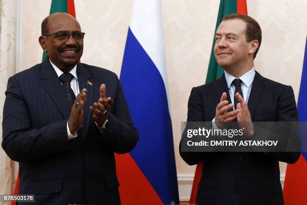 Russian Prime Minister Dmitry Medvedev and Sudanese President Omar al-Bashir applaud during a signing ceremony following their meeting in Sochi on...