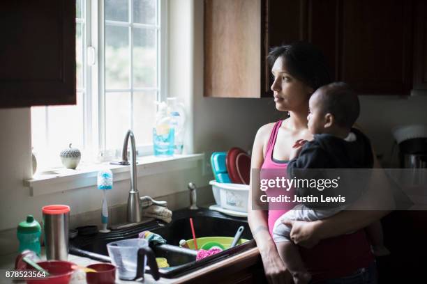 Modern Native American Mother and Baby Share a Cuddly Moment While Doing Dishes in the Kitchen