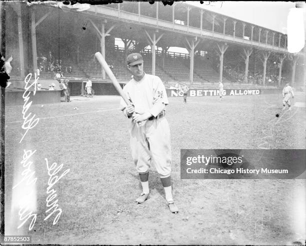 Informal full-length portrait of baseball player Merkle of the National League's New York Giants, holding a baseball bat, standing on the field at...