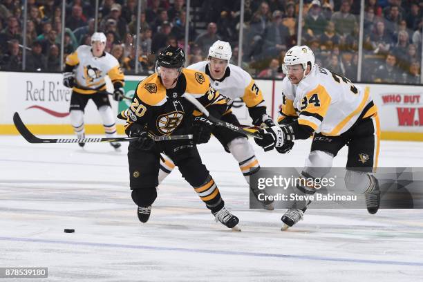 Riley Nash of the Boston Bruins skates after the puck against Greg McKegg and Tom Kuhnhackl of the Pittsburgh Penguins at the TD Garden on November...