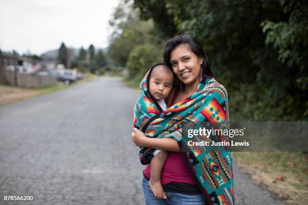 young native american mother and baby standing on paved street, smiling - aboriginal family stock-fotos und bilder