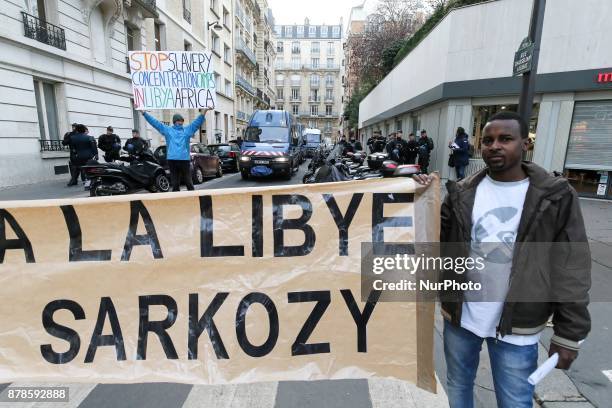 Man holds a banner against the French former president Sarkozy during a demonstration against slavery in Libya on November 24 outside the Libyan...