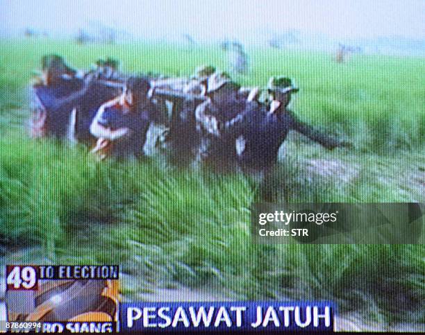 In this television image from Metro Televion shows civilian and military rescuers recovering victims at the crash site littered with debris of plane...