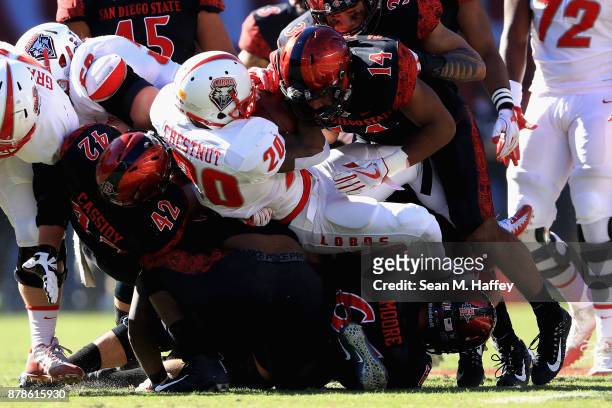 Troy Cassidy and Tariq Thompson of the San Diego State Aztecs tackle Daryl Chestnut of the New Mexico Lobos during the first half of a game at...