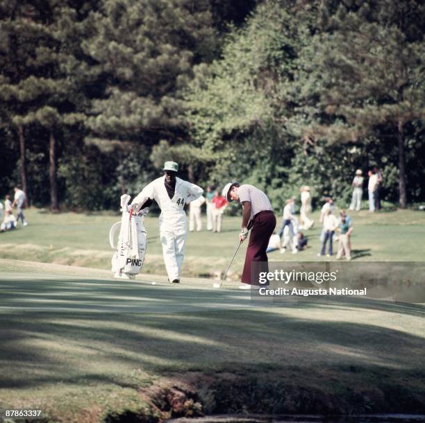 Jim Colbert watches his putt on the Par 3 with his caddie during the 1976 Masters Tournament at Augusta National Golf Club on April 1976 in Augusta,...