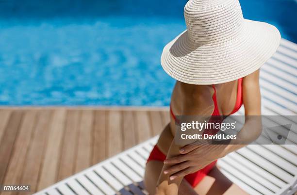 young woman applying  sunscreen by swimming pool - sun hat 個照片及圖片檔