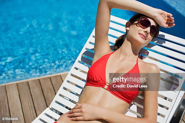 young woman on sun lounger by swimming pool - 日光浴 ストックフォトと画像