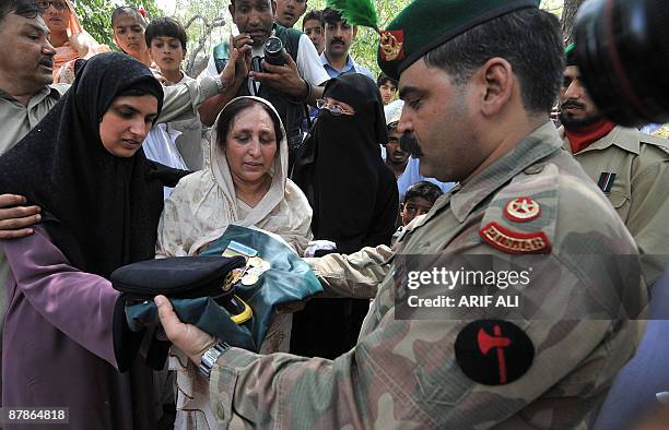 Pakistani army officer hands over medal bars, cap and national flag to the mother and wife of Major Abid Majeed Malik, a Pakistan�s army Major Abid...