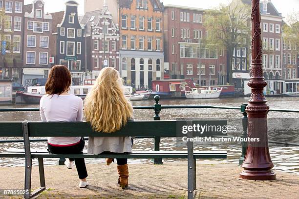 amsterdam girls sitting on bench viewing the water - amsterdam stock pictures, royalty-free photos & images