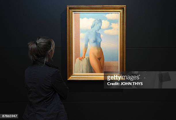 Visitor attends the press opening of the new Magritte museum dedicated to the life and works of Belgian artist Rene Magritte in front of the painting...