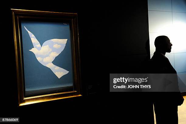 Security guard looks on as he stands beside a painting entitled " Sky Bird 1966 " by the Belgian artiste Rene Magritte at the press opening of the...