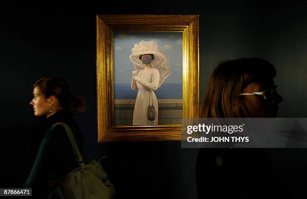 Visitors walk past a painting by the Belgian artiste Rene Magritte at the press opening of the new Margitte museum in Brussels on May 20, 2009. The...