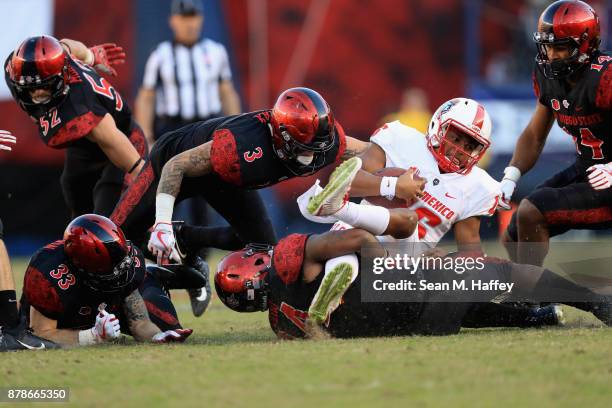 Trey Lomax, Parker Baldwin and Tariq Thompson of the San Diego State Aztecs tackle Tevaka Tuioti of the New Mexico Lobos during the second half of a...