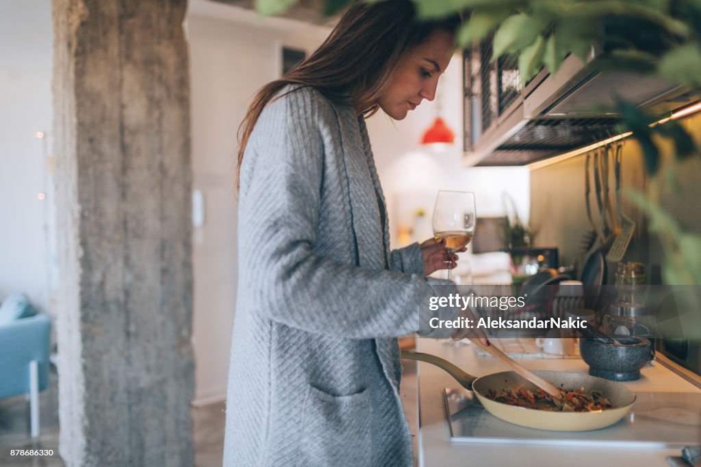 Young woman cooking and drinking wine