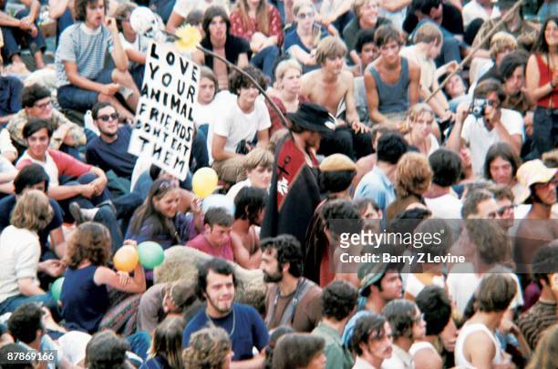 An unidentified festival goer carries a banner that reads 'Love Your Animal Friends; Don't Eat Them' as he leads a sheep through a portion of the...
