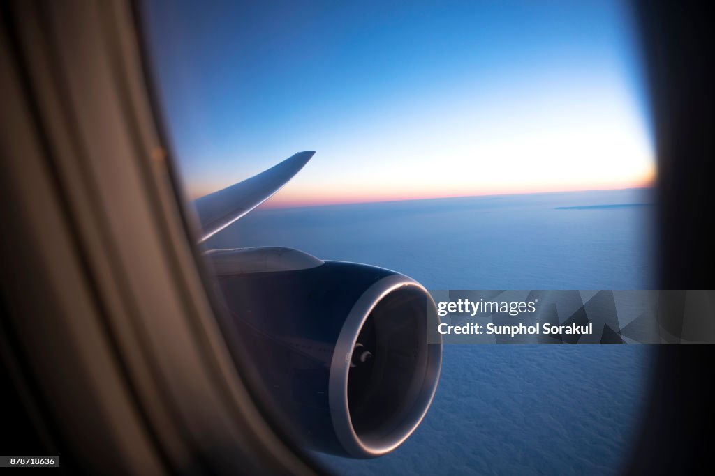 View of a sun set over with cloudscape through the aircraft porthole window