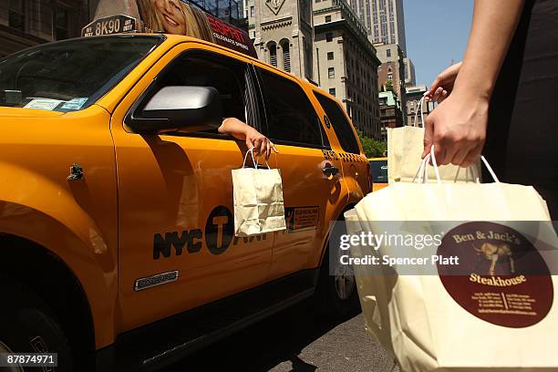 An employee hands out a free bagged lunch to a taxi driver, compliments of Ben & Jacks Steakhouse on May 20, 2009 in New York City. The restaurant...