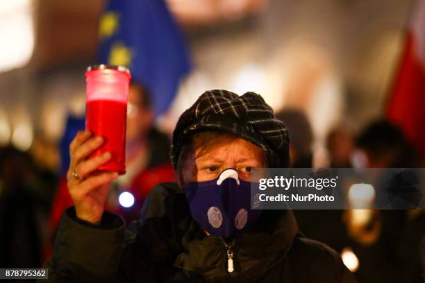 Woman wearing an anti-smog mask holds a candle during a protest at the Main Square against government plans for sweeping changes to Polands judicial...