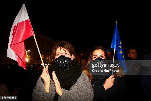 Women wearing an anti-smog mask hold Polish and EU flags during a protest at the Main Square against government plans for sweeping changes to Polands...