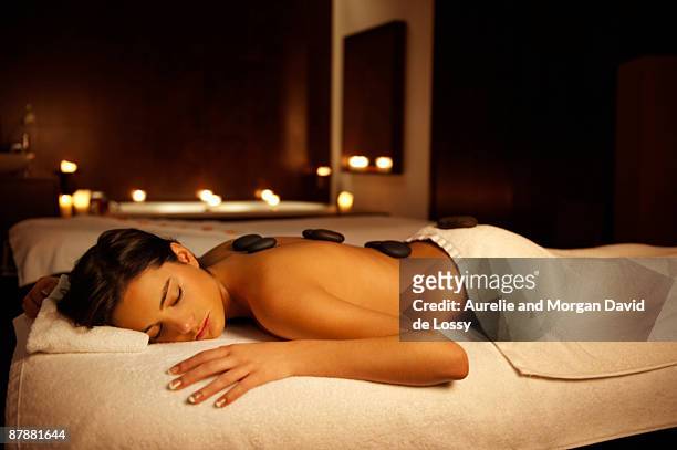 woman receiving hot stone massage - terapia lastone fotografías e imágenes de stock