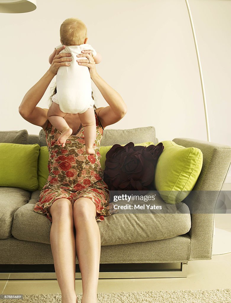 Mother holding up baby,  faces hidden