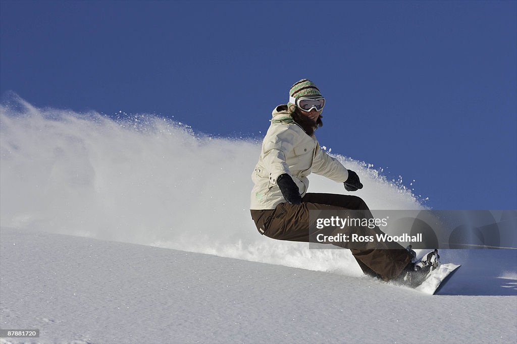 Female snowboarder turning off piste