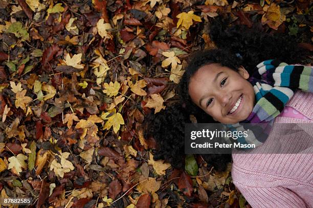 girl lying on autumn leaves - children only stock pictures, royalty-free photos & images