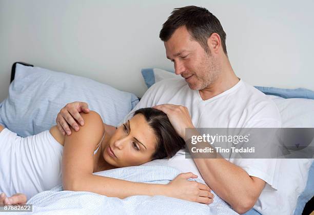 young couple relaxing at home - man and woman cuddling in bed stockfoto's en -beelden