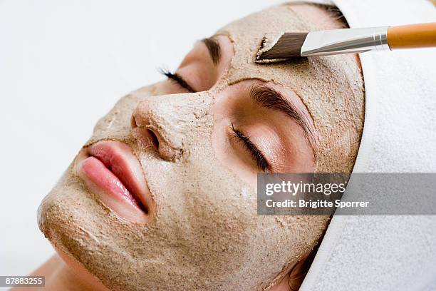 woman getting face mask - clay mask ストックフォトと画像