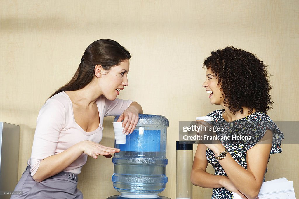 Two women are chatting by water cooler